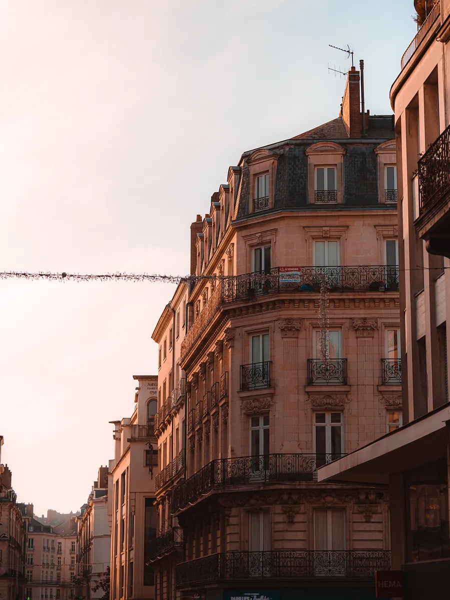 A stone apartment building with wrought-iron balconies glowing in late afternoon light.