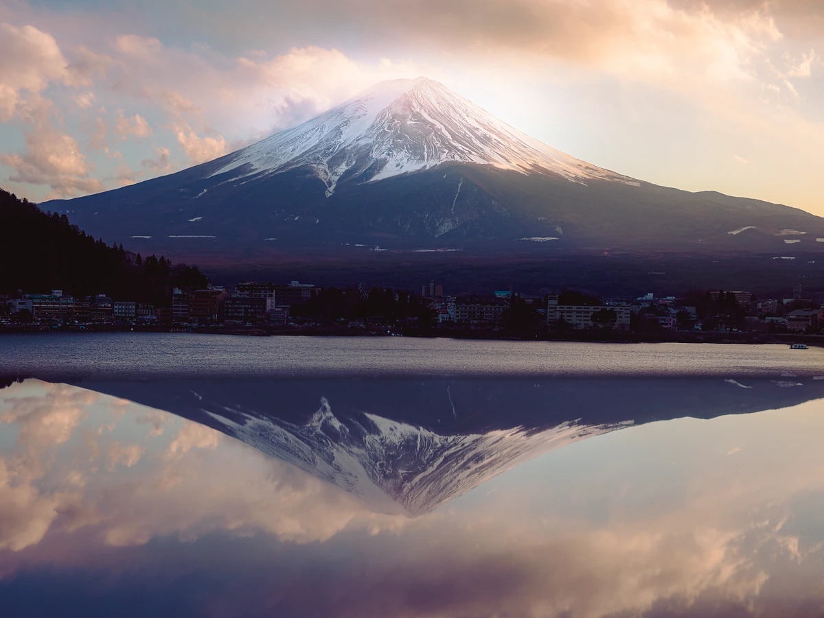 Mount Fuji mirrored in Lake Kawaguchi under soft pink and violet dusk clouds.